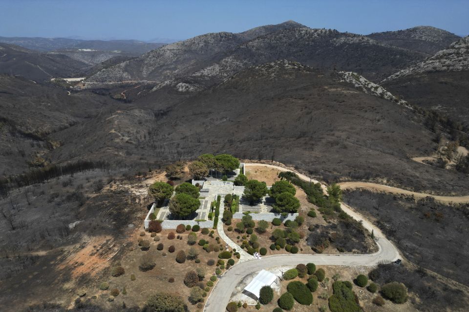 Blackened mountains are seen around the German Military Cemetery, which had been burned in a mid-August wildfire, at Dionysos, a northern suburb of Athens, Thursday. [Thanassis Stavrakis/AP]